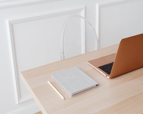 A neat home office desk with a closed laptop and a notebook