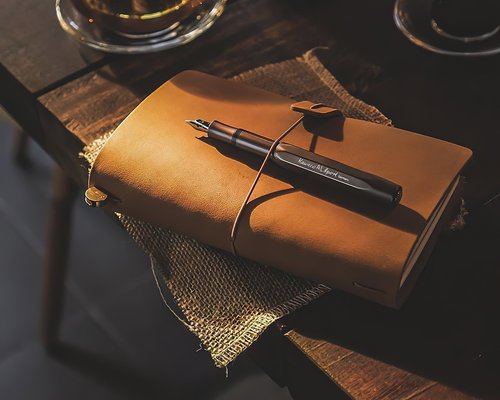 A notebook and pen on an office desk, ready for writing